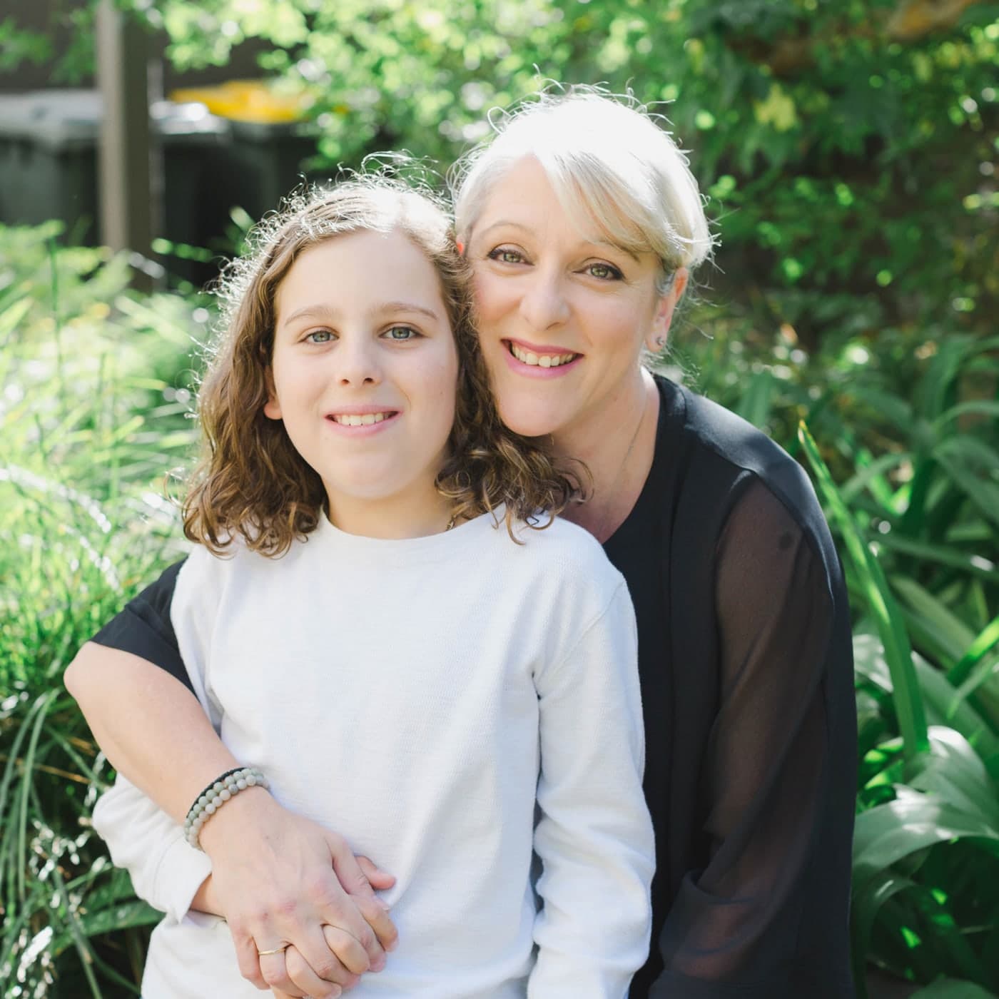 Fay, founder of Aphora Botanicals, in a garden with her son — the child whose eczema sent her to the skincare aisle and then to formulation textbooks.